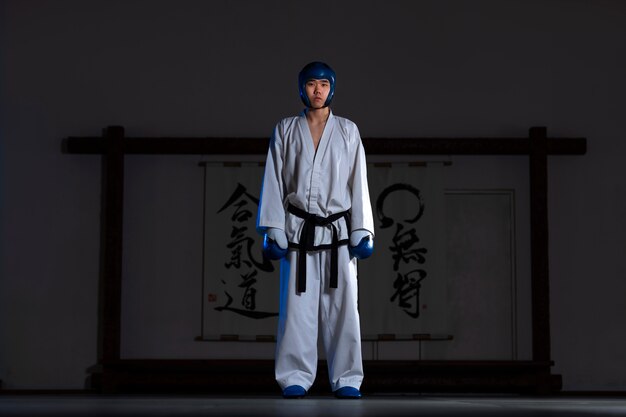 Uomo asiatico del colpo pieno che pratica taekwondo