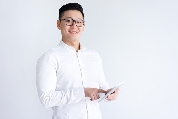 Uomo asiatico sorridente che per mezzo del calcolatore del ridurre in pani