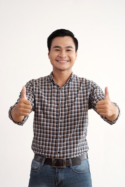 Uomo asiatico sorridente che posa nello studio con i pollici in su