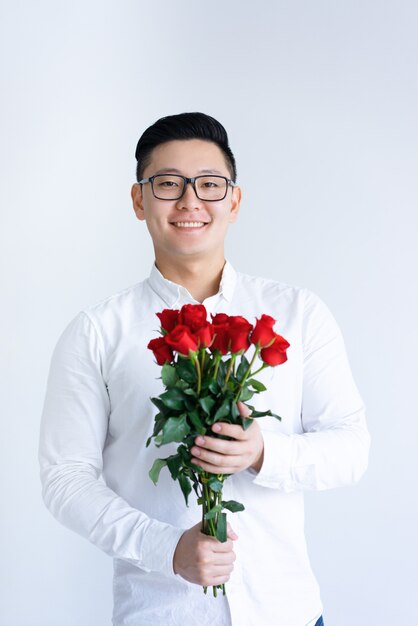 Uomo asiatico sorridente che tiene mazzo di rose