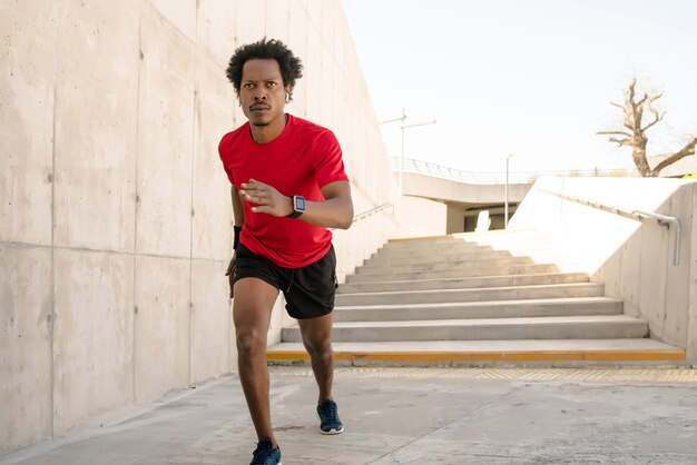 Uomo atletico afro che corre e fa esercizio all'aperto per strada. Sport e concetto di stile di vita sano.