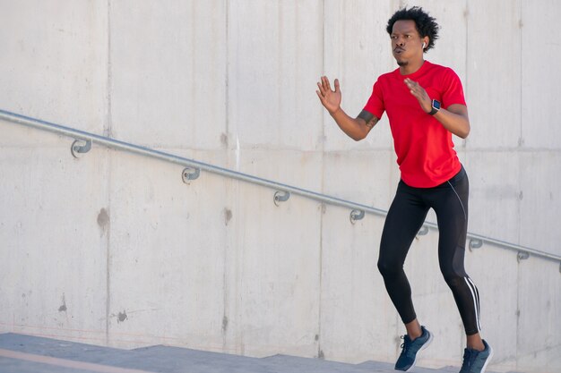 Uomo atletico afro che fa esercizio all'aperto alle scale. Sport e stile di vita sano.