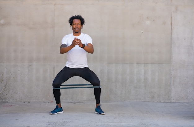 Uomo atletico afro che si esercita e che fa la gamba squat all'aperto. Sport e concetto di stile di vita sano.