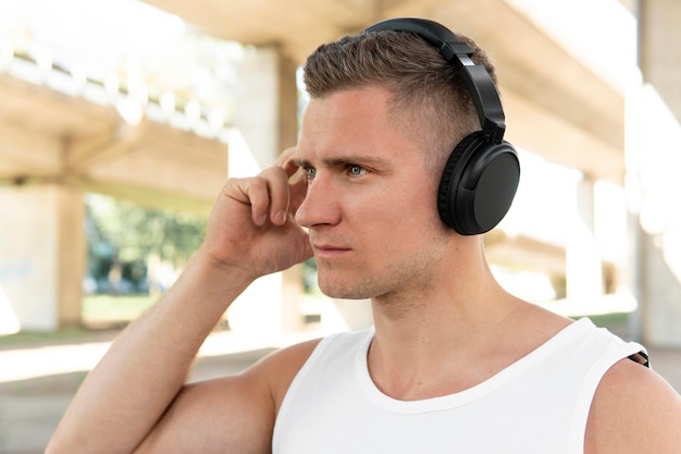 Uomo atletico lateralmente che distoglie lo sguardo mentre ascoltando la musica