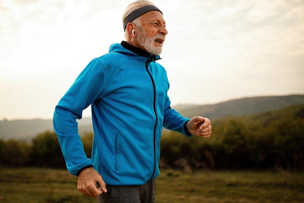 Uomo atletico maturo che esce senza fiato mentre fa jogging al mattino nella natura