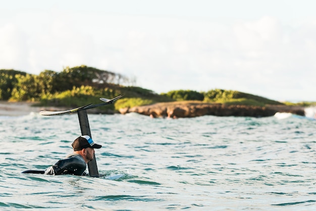 Uomo attivo in attrezzatura speciale che soggiorna su una tavola da surf