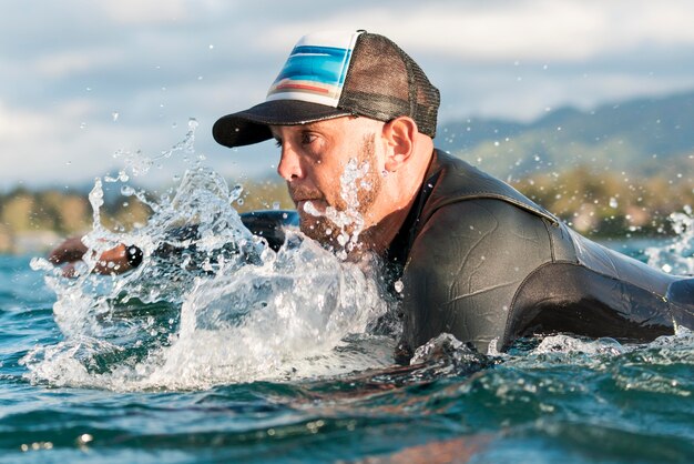 Uomo attivo in attrezzatura speciale che soggiorna su una tavola da surf