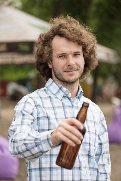 Uomo attraente che si distende sulla spiaggia con la birra