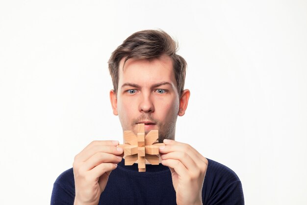 Uomo attraente di affari di 25 anni che sembra sconcertante il puzzle di legno.