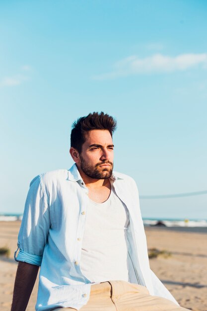 Uomo attraente sulla spiaggia che osserva via