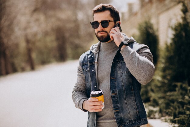 Uomo barbuto bello che beve caffè fuori dalla strada