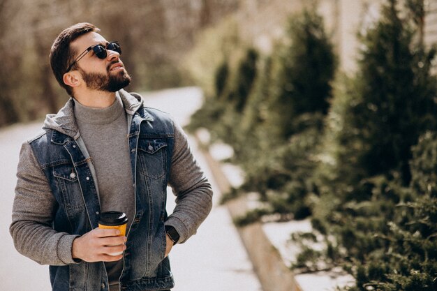 Uomo barbuto bello che beve caffè fuori dalla strada