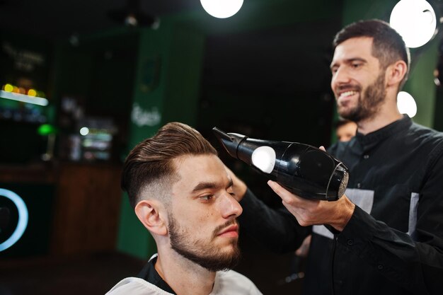Uomo barbuto bello dal barbiere barbiere al lavoro