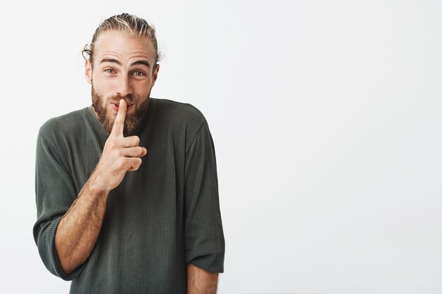 Uomo barbuto bello divertente che fa gesto di mano di silenzio che chiede silenzioso