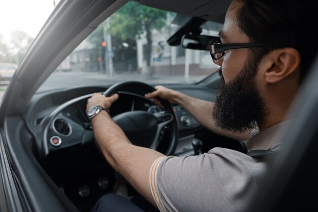 Uomo barbuto casual moderno alla guida di un'auto