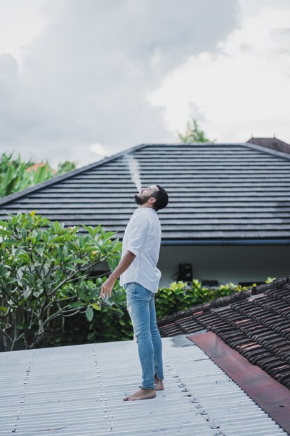 Uomo barbuto che fuma sul tetto