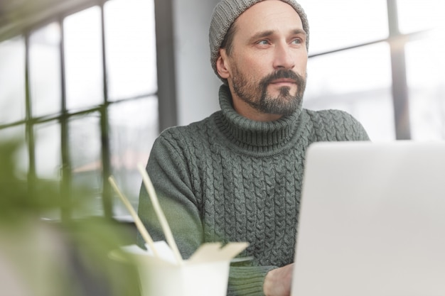 Uomo Barbuto che indossa un maglione caldo lavorato a maglia e cappello a pranzo