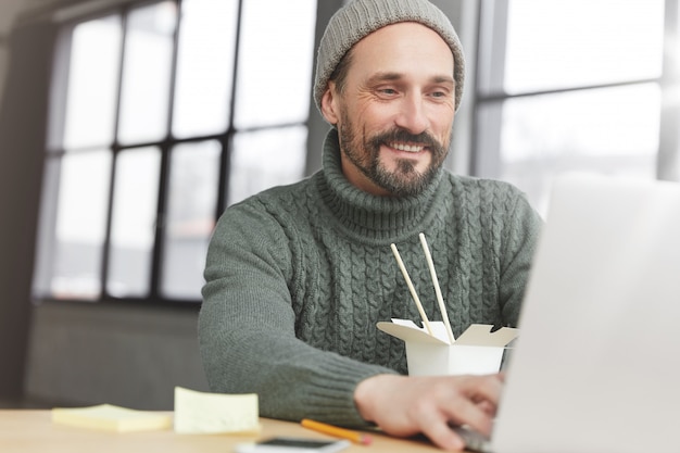 Uomo Barbuto che indossa un maglione caldo lavorato a maglia e cappello a pranzo