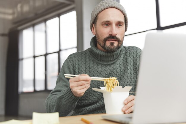 Uomo Barbuto che indossa un maglione caldo lavorato a maglia e cappello a pranzo