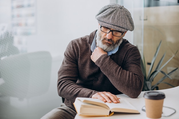 Uomo barbuto che legge un libro e si siede al tavolo