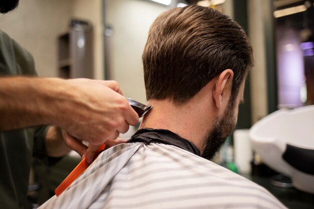 Uomo barbuto che si fa tagliare i capelli dal barbiere