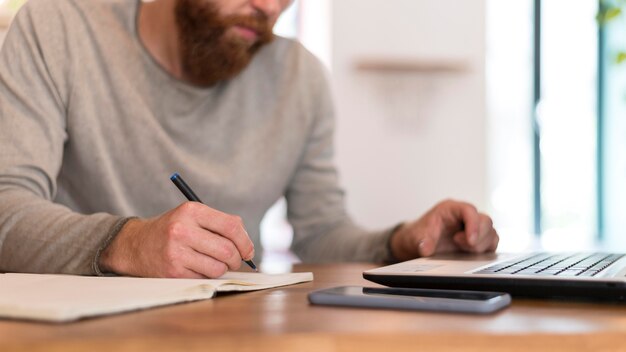 Uomo barbuto di lato che prende appunti al lavoro