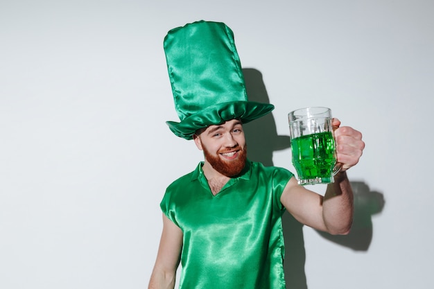 Uomo barbuto felice in costume verde che tiene tazza