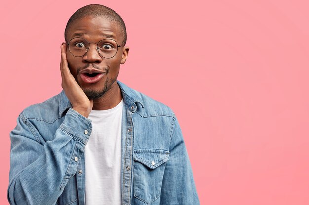 Uomo barbuto in camicia di jeans e occhiali rotondi