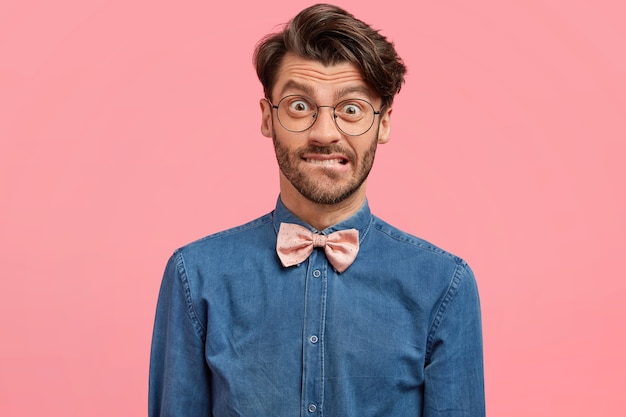 Uomo barbuto in camicia di jeans e papillon rosa