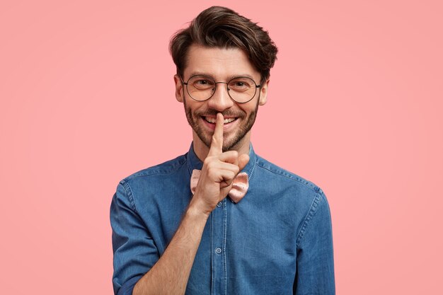 Uomo barbuto in camicia di jeans e papillon rosa