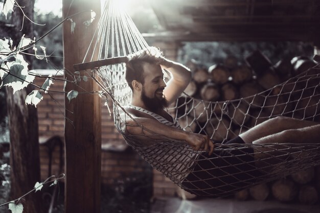 uomo barbuto sdraiato amaca in una calda giornata estiva