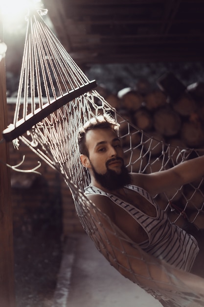 uomo barbuto sdraiato amaca in una calda giornata estiva