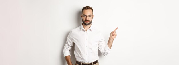 Uomo barbuto serio che punta il dito a sinistra che mostra la pubblicità in piedi su sfondo bianco