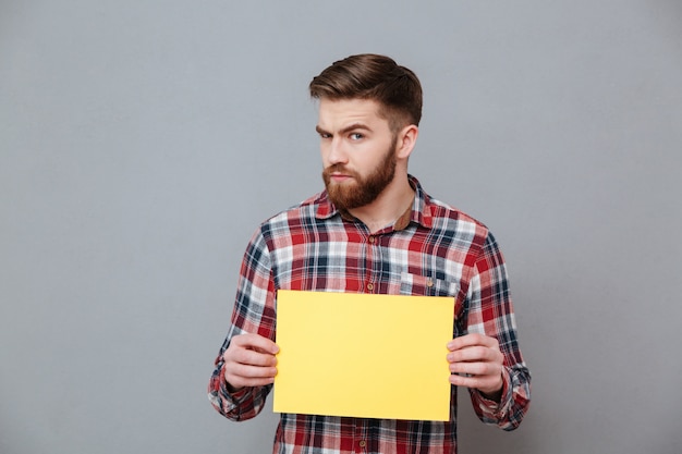 Uomo barbuto serio che tiene carta in bianco