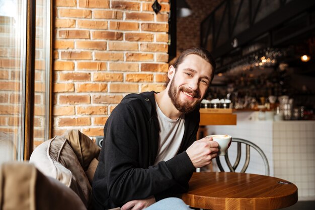 Uomo barbuto sorridente in caffè
