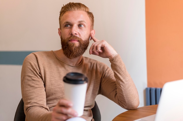 Uomo barbuto vista frontale che tiene una tazza di caffè