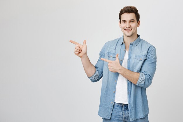 Uomo bello amichevole che indica le dita lasciate alla pubblicità