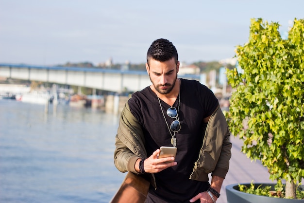 Uomo bello che comunica sul telefono all&#39;aperto. Con giacca, sunglas