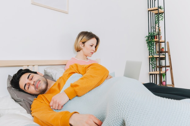 Uomo bello che dorme vicino alla donna con il computer portatile