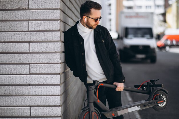 Uomo bello che guida in città su scooter