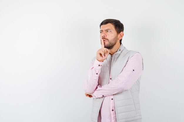 Uomo bello che mostra gesto di silenzio in maglia, camicia e sembra serio,