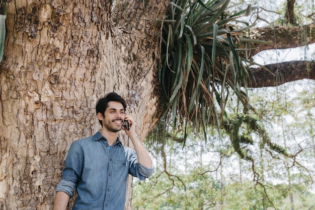 Uomo bello che parla sul telefono nel parco