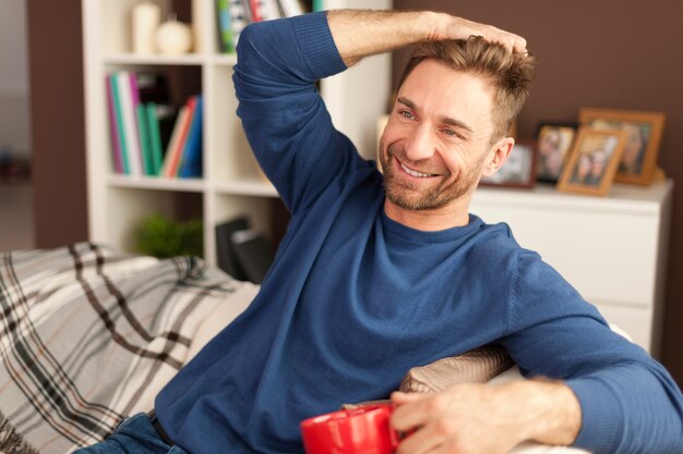 Uomo bello che si distende con una tazza di caffè a casa