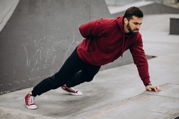 Uomo bello che si esercita nel parco nell'usura di sport