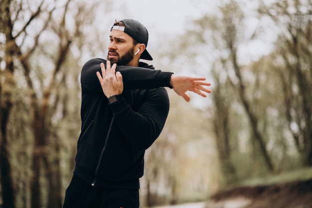 Uomo bello che si esercita nel parco nell'usura di sport