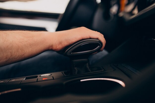 Uomo bello che si siede in automobile e che lo prova