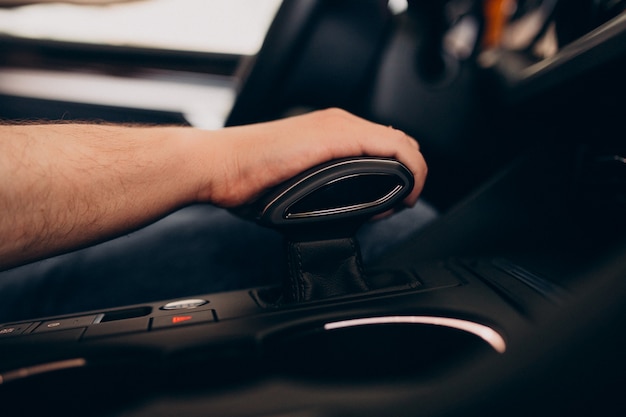 Uomo bello che si siede in automobile e che lo prova