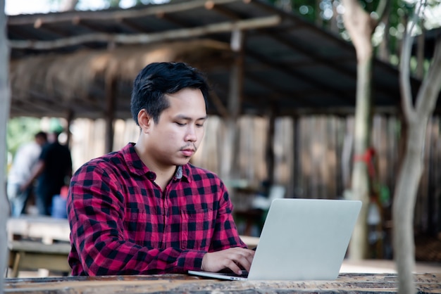 Uomo bello che utilizza computer portatile nella natura di viaggio