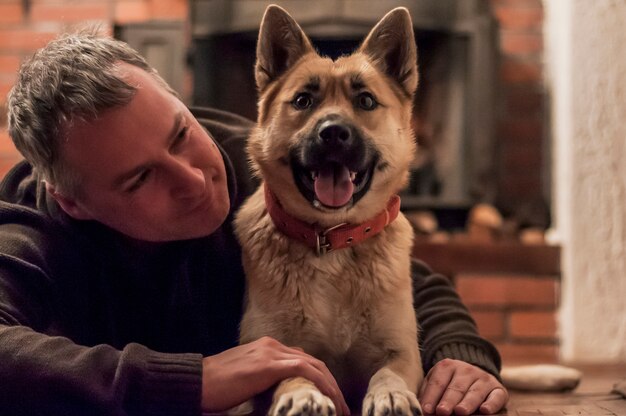 Uomo bello con cane carino a casa. Uomo attraente che giace sul pavimento con il suo cane a casa nel salotto. Emozioni umane positive, espressioni facciali, sentimenti.