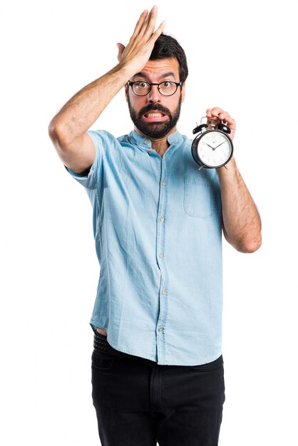 Uomo bello con gli occhiali blu che tiene orologio